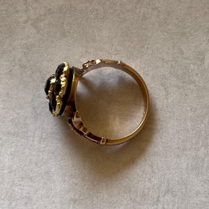 May include: A gold ring with a black gemstone cluster set in a flower shape.