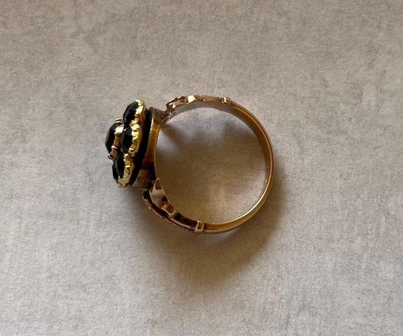 May include: A gold ring with a black gemstone cluster set in a flower shape.
