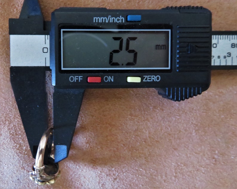 May include: A close-up of a digital caliper measuring a ring. The caliper reads 2.5 mm.