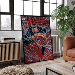 May include: A framed comic book cover of The Amazing Spider-Man issue 6, featuring a red and blue costumed character entangled in white webbing against a solid red background, with the Marvel logo and title text clearly visible at the top.