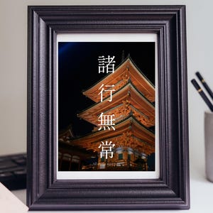 Pode incluir: Uma moldura retangular preta contendo uma impressão de um pagode de madeira de vários níveis iluminado à noite. A impressão apresenta os caracteres kanji japoneses 諸行無常 alinhados verticalmente em branco, com o texto em inglês All things must pass abaixo.