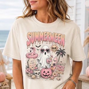 May include: An ivory short-sleeve t-shirt featuring a graphic print with the text SUMMERWEEN. The design includes a ghost wearing heart-shaped sunglasses, a pink flamingo float, a pumpkin, a skull, a surfboard, and tropical beach elements.