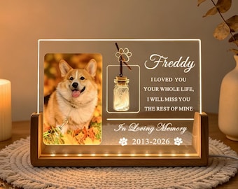 May include: A rectangular acrylic memorial plaque with a wooden base, featuring a photo of a corgi, a small hanging glass jar charm, and engraved text reading Freddy, I loved you your whole life, I will miss you the rest of mine, In Loving Memory 2013-2026.