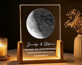 May include: A rectangular acrylic plaque with a light-up moon and star graphic, featuring the text "Jennifer & Stephen," "THE NIGHT OUR ADVENTURE BEGAN...", "SOMERSET, ENGLAND | 51.0635° N, 2.7547° W," and "26TH SEPTEMBER 2015" in a wooden base.