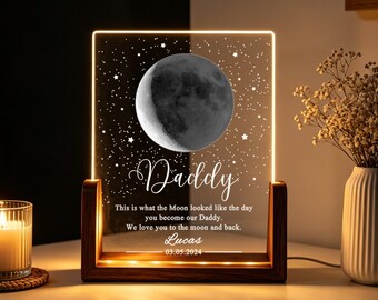 May include: A rectangular acrylic night light set in a dark wooden base, featuring a glowing moon graphic, a star-filled sky, and the text: "Daddy. This is what the Moon looked like the day you become our Daddy. We love you to the moon and back. Lucas 03.05.2024."