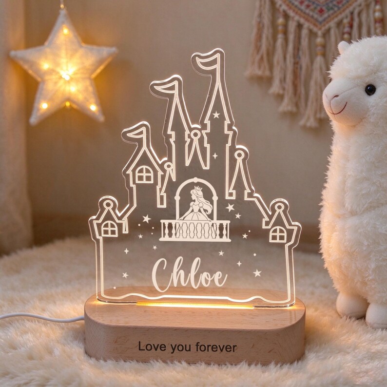 Puede incluir: Una luz nocturna de acr&iacute;lico transparente con forma de castillo, una silueta de princesa, estrellas y el nombre Chloe grabado. Se apoya sobre una base de madera clara con el texto grabado Love you forever en la parte frontal.