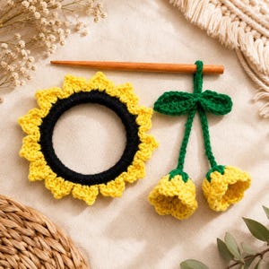 Può includere: Un elastico per capelli a forma di girasole all'uncinetto con centro nero e petali gialli, abbinato a un bastoncino per capelli in legno con due boccioli di fiore gialli pendenti su steli verdi con foglie verdi, realizzati in filato.