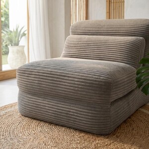 May include: A low-profile armless chair upholstered in a taupe-coloured corduroy fabric. The chair features a segmented design with a thick, cushioned seat and a backrest composed of two horizontal, ribbed sections, creating a soft, rounded silhouette.