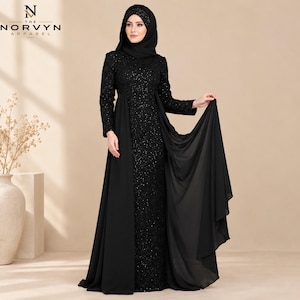 Op de afbeelding: Een zwarte avondjurk tot op de grond met een lovertjeslijfje en lange mouwen, gecombineerd met een bijpassende zwarte hijab. De jurk heeft een effen zwarte chiffon overlay die vanaf de taille valt, wat een gelaagd effect met een hoge halslijn creëert.