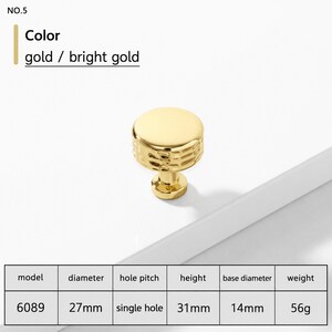 May include: A bright gold cabinet knob, model 6089, featuring a smooth circular top and a textured side. The knob has a 27mm diameter, 31mm height, 14mm base diameter, and weighs 56g. It is designed for a single hole installation.