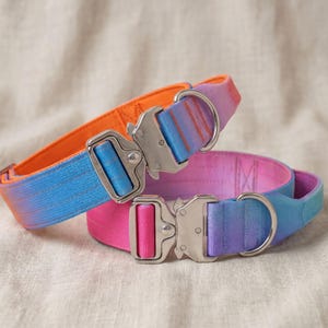 May include: Two pet collars featuring vibrant ombre nylon webbing. The top collar transitions from orange to blue, while the bottom collar shifts from pink to purple. Both collars are equipped with heavy-duty silver metal quick-release buckles.