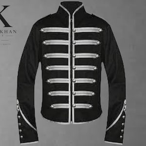 Könnte beinhalten: Eine schwarze Jacke im Militärstil mit Stehkragen, langen Ärmeln und einem Frontverschluss mit silberfarbenen Knöpfen sowie horizontalen silbernen Paspeln. Die Ärmelabschlüsse sind mit silbernen Paspeln und kleinen Knöpfen verziert.