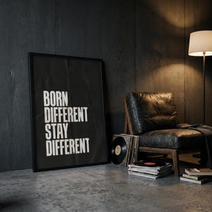 Op de afbeelding: Een rechthoekig kunstwerk in een zwarte lijst met de witte tekst BORN DIFFERENT STAY DIFFERENT in een vetgedrukt schreefloos lettertype. De poster is verticaal georiënteerd en heeft een contrastrijk ontwerp op een donkere achtergrond.