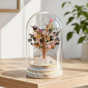 May include: A decorative tree sculpture made of copper wire and multi-colored gemstone chips, including pink, green, and dark grey stones. The tree is mounted on a circular wooden base and enclosed within a clear, dome-shaped glass cloche.