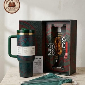 May include: A dark green insulated tumbler with a handle and a patterned design, featuring a matching gift box with the text 20 26, a green velvet pouch, and a clear straw. The tumbler has a white product information band wrapped around it.