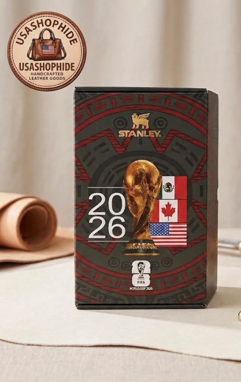 May include: A rectangular Stanley brand box featuring a dark green and red patterned design. The front displays the text 2026, a gold FIFA World Cup trophy graphic, the FIFA World Cup 2026 logo, and the flags of Mexico, Canada, and the United States.