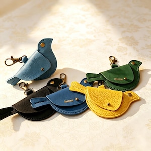 May include: A collection of bird-shaped keychains in blue, black, and yellow, each featuring a metal lobster clasp, a snap button closure, and the word MIRIN embossed on the side. These small accessories are crafted with a textured finish.