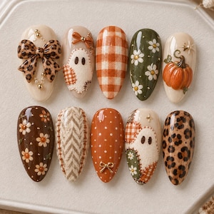 Peut inclure: Un ensemble de dix faux ongles en forme d'amande avec des motifs sur le thème de l'automne, incluant un nœud léopard, un fantôme, un vichy orange, des marguerites blanches sur fond vert olive, une citrouille, des fleurs et des motifs patchwork.