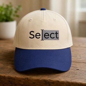 May include: A cream-colored baseball cap with a dark blue brim. The front features the embroidered black text "Select" with a vertical cursor line and a grey rectangular highlight box over the letters "ect" to mimic a computer text selection.