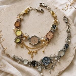 May include: Two decorative chains featuring multiple vintage-style wristwatches in gold and silver tones. The gold chain includes various watch faces, pearls, and small charms. The silver chain features silver-toned watch faces, pearls, and charms.