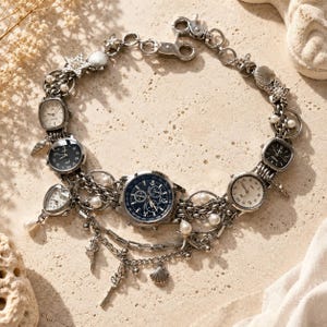 May include: A silver-toned charm bracelet featuring multiple miniature analog watch faces with black and white dials, interspersed with small white pearls, metallic starfish, and seashell charms, connected by a sturdy link chain with a lobster clasp.