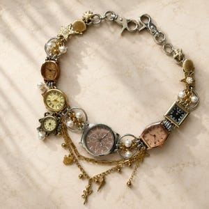 May include: A decorative chain necklace featuring multiple vintage-style watch faces in gold, silver, and rose gold tones, interspersed with white faux pearls, gold-toned starfish charms, and seashell accents, finished with a silver-toned lobster clasp.