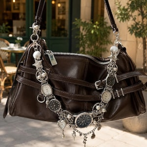 May include: A dark brown handbag featuring a silver-toned chain strap adorned with multiple small analog wristwatches, white pearls, and silver seashell and starfish charms. The bag has a zippered top closure and decorative buckled straps.