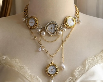 May include: A gold-toned chain necklace featuring three round analog watch faces and one central heart-shaped watch face, all with white dials. The piece is adorned with multiple white faux pearls, delicate gold chains, and a single teardrop pearl pendant.