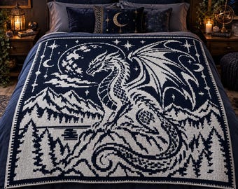 May include: A dark blue and white knit blanket featuring a large dragon centered in front of a full moon, mountain range, and forest landscape. The design includes celestial stars and crescent moons, with a decorative border framing the scene.