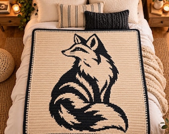May include: A rectangular crochet blanket featuring a large, dark navy blue fox silhouette centered on a cream-colored background. The blanket has a dark navy blue border with a small, repeating white dot pattern along the outer edge.