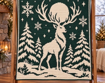 May include: A dark green and cream crochet blanket featuring a large stag with antlers framing a full moon, surrounded by pine trees, snowflakes, and small stars. The rectangular textile displays a detailed winter forest scene.