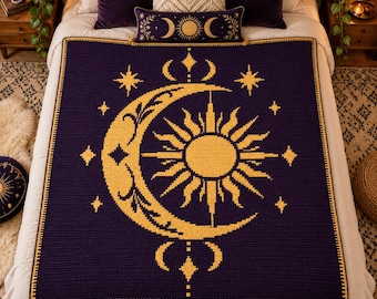 May include: A dark purple crochet blanket featuring a large yellow sun and crescent moon design at the center, surrounded by small star motifs. The blanket has a thick yellow border and is displayed on a bed with matching decorative pillows.