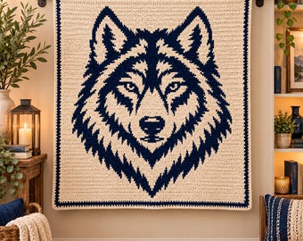 May include: A square crochet blanket featuring a large, centered dark navy blue wolf head graphic against a cream-colored background. The blanket is bordered by a dark navy blue edge and is displayed hanging from a horizontal rod.