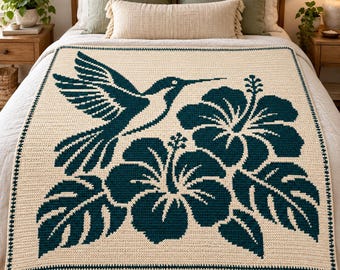 May include: A rectangular crochet blanket featuring a cream-colored base with a dark teal pattern. The design displays a hummingbird in flight positioned above two large hibiscus flowers and several tropical leaves, finished with a dark teal border.