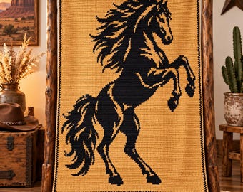 May include: A rectangular crochet blanket featuring a large, black, rearing horse silhouette centered on a solid mustard yellow background. The blanket has a simple black border around the edges and is displayed hanging on a wooden frame.