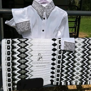May include: A white long-sleeved shirt with black crystal-embellished collar and cuffs, paired with a white, black, and silver patterned saddle pad featuring the text SHOWWESTERN WRAPCO and a horse head graphic logo.