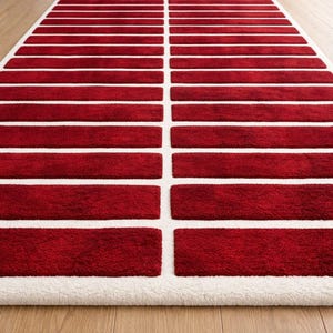 May include: A rectangular area rug featuring a repeating pattern of deep red, horizontal rectangular blocks separated by a crisp white grid. The design consists of two columns of these red segments, framed by a thick white border on all sides.