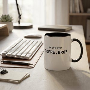 Puede incluir: Una taza de cerámica blanca con interior y asa de color negro. El exterior presenta el texto impreso en negro "Do you even TOPRE, BRO?" en una fuente sans-serif. La taza es cilíndrica con un acabado liso y un asa en forma de C.