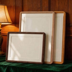 May include: Three rectangular wooden picture frames with rounded corners and off-white matting. The frames are arranged in a staggered formation, featuring varying wood tones ranging from dark brown to light natural wood, each with a smooth finish.
