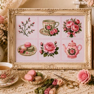 May include: A framed cross-stitch embroidery featuring six distinct panels: a floral sprig, a teacup on a saucer, a bouquet of pink roses, a plate of macarons, a single large rose, and a pink teapot, all rendered in shades of pink and green.