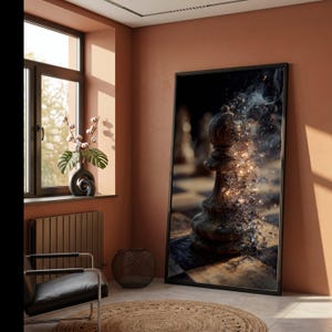Op de afbeelding: Een grote ingelijste wandkunstprint met een close-up van een houten schaakstuk, een loper, op een schaakbord. De rechterkant van het schaakstuk lijkt uiteen te vallen in gloeiende gouden deeltjes en rookpluimen tegen een donkere achtergrond.