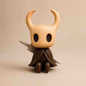 May include: A wooden figurine of a character with a light tan, smooth, horned head and large, dark, oval-shaped eye sockets. The figure wears a dark brown, textured cloak and has a silver-colored, pointed sword positioned behind its back.