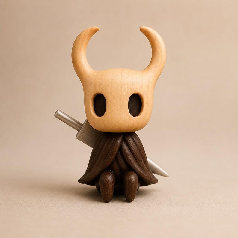 May include: A wooden figurine of a character with a light tan, smooth, horned head and large, dark, oval-shaped eye sockets. The figure wears a dark brown, textured cloak and has a silver-colored, pointed sword positioned behind its back.