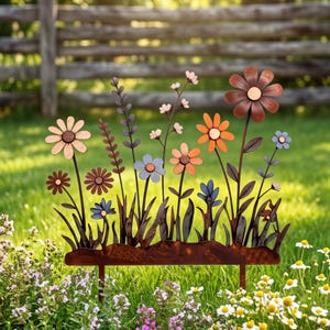 Könnte beinhalten: Ein Gartenstecker aus Metall mit einer Ansammlung stilisierter Blumen in Rost-, Orange- und Hellblautönen. Das Design umfasst verschiedene Blumenformen, dünne Stiele und Blätter, die alle auf einer soliden, horizontalen Basis mit zwei Erdspießen befestigt sind.