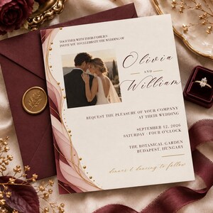 Puede incluir: Una tarjeta de invitación de boda con una foto de una pareja, con el texto Olivia and William, 12 de septiembre de 2026, y The Botanical Garden, Budapest, Hungría. El diseño incluye ondas abstractas rosas y burdeos con puntos dorados.