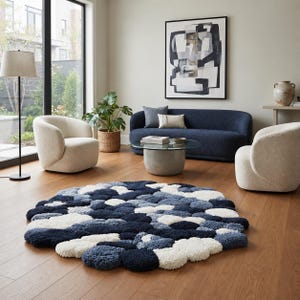 May include: A circular area rug featuring a textured, pebble-like design composed of plush, rounded tufts in varying shades of navy blue, slate blue, and cream white, creating a dimensional surface that rests flat on a wooden floor.