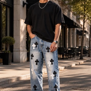 May include: Light blue denim jeans featuring a scattered pattern of black and white cross-shaped patches. The jeans have a straight-leg fit with a classic five-pocket design, a button fly closure, and visible stitching along the seams and pockets.