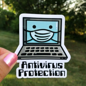 May include: A white sticker featuring a cartoon laptop wearing a face mask. The laptop screen is light blue with black eyes. The sticker has the words "Antivirus Protection" in a bold, black font.