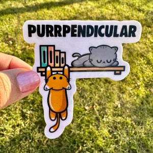 May include: A white sticker with the text "PURRPENDICULAR" in black letters. The sticker features a cartoon orange cat hanging from a shelf with books on it. A gray cat is sleeping on the shelf.