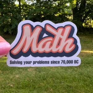 May include: A white sticker with a pink and blue "Math" graphic and the text "Solving your problems since 70,000 BC".